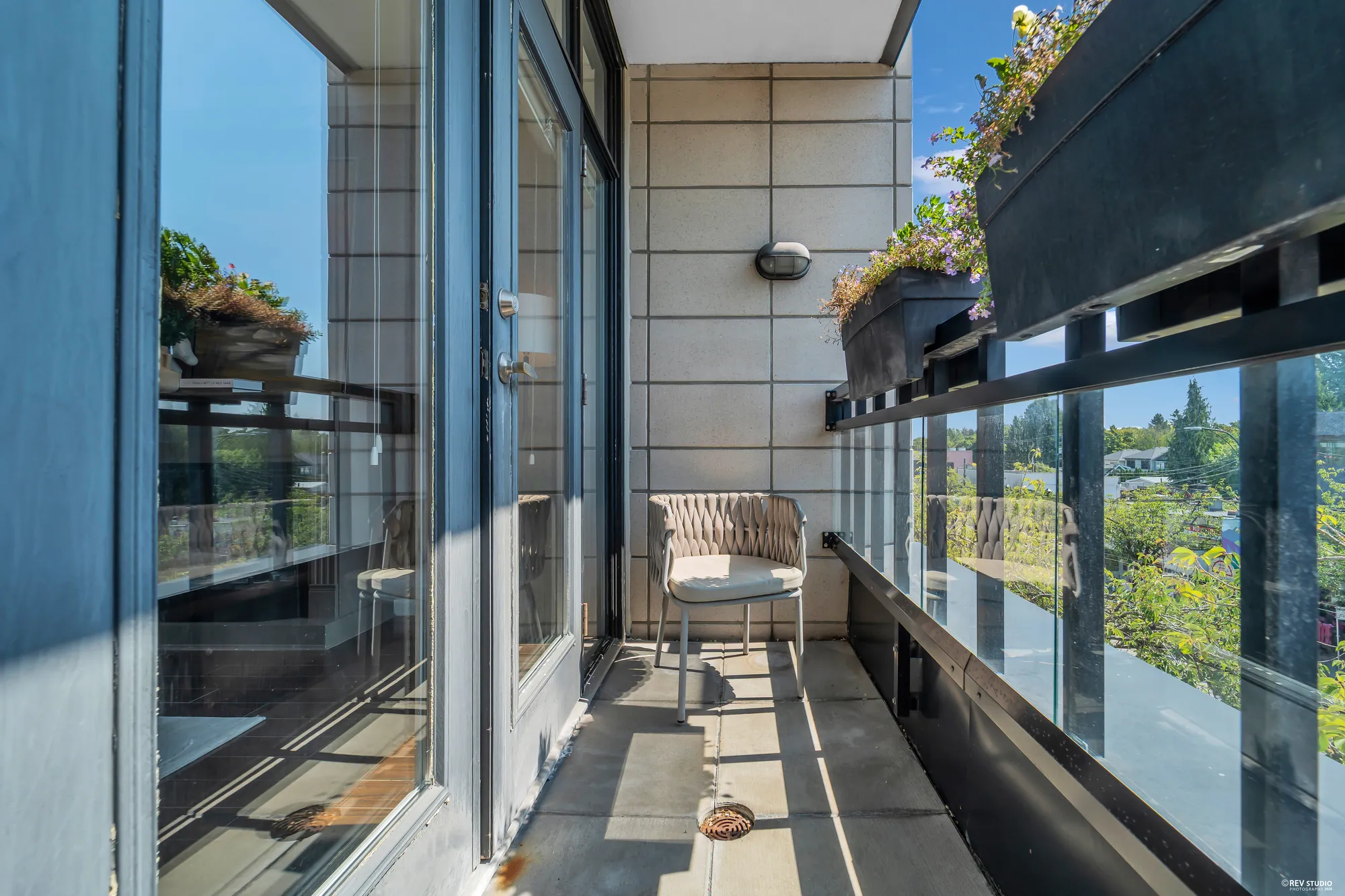 The balcony with a chair, glass railing and planters along the edge