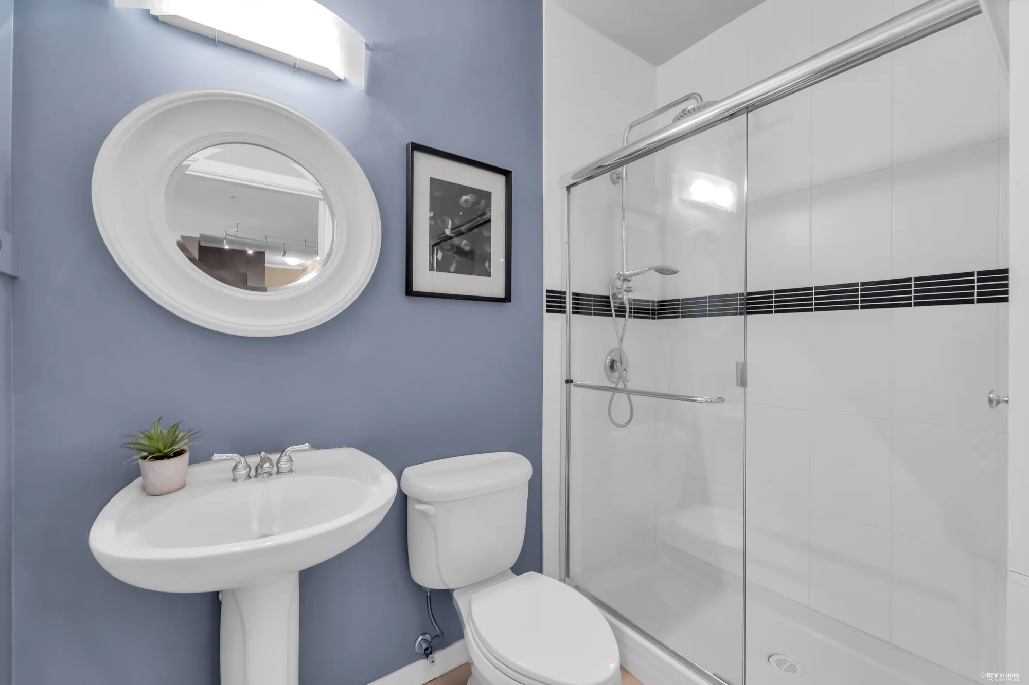 The three-piece bathroom with a glass shower and a pedestal basin