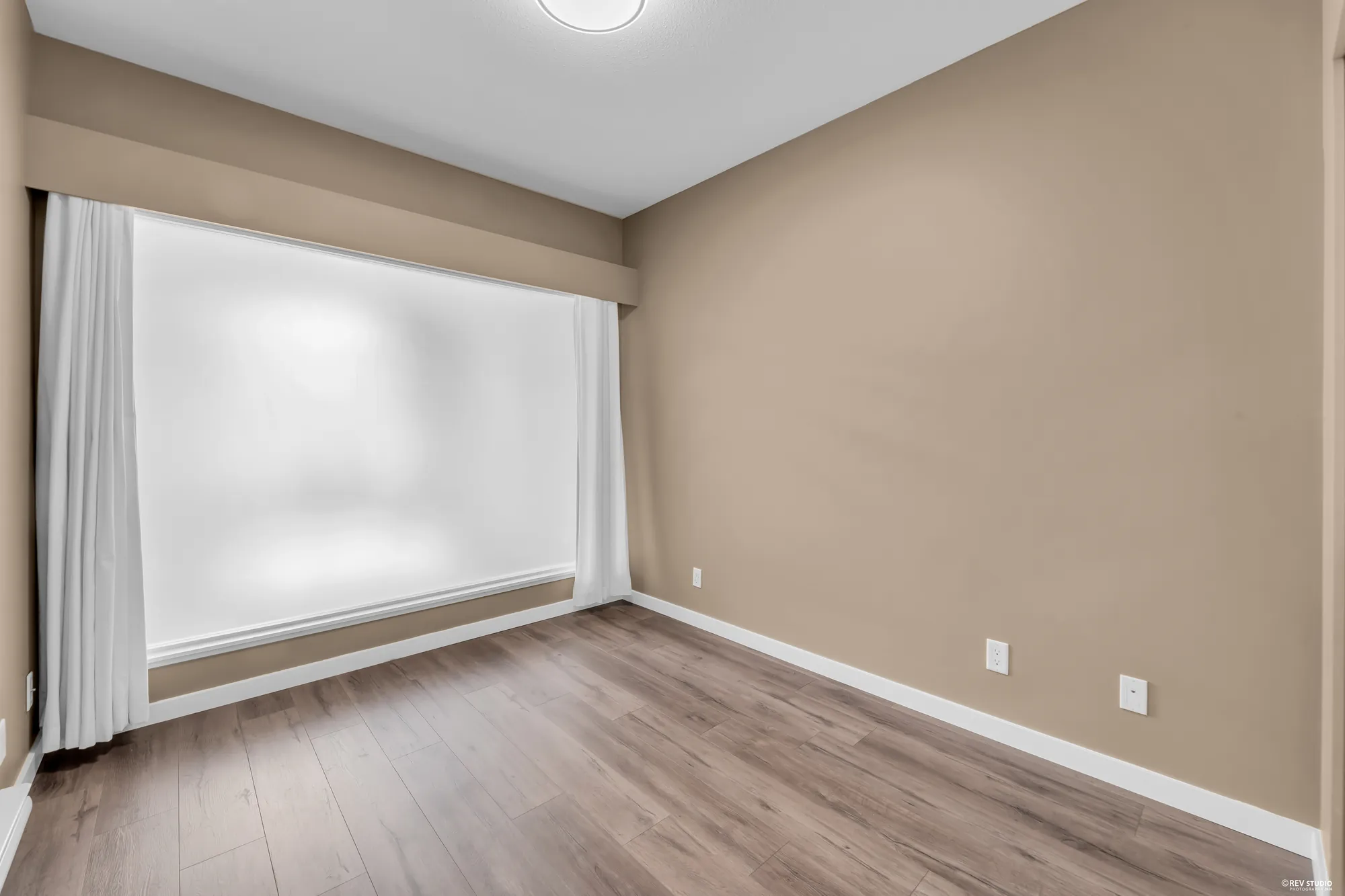 The second bedroom photographed empty, a wide window across the far wall
