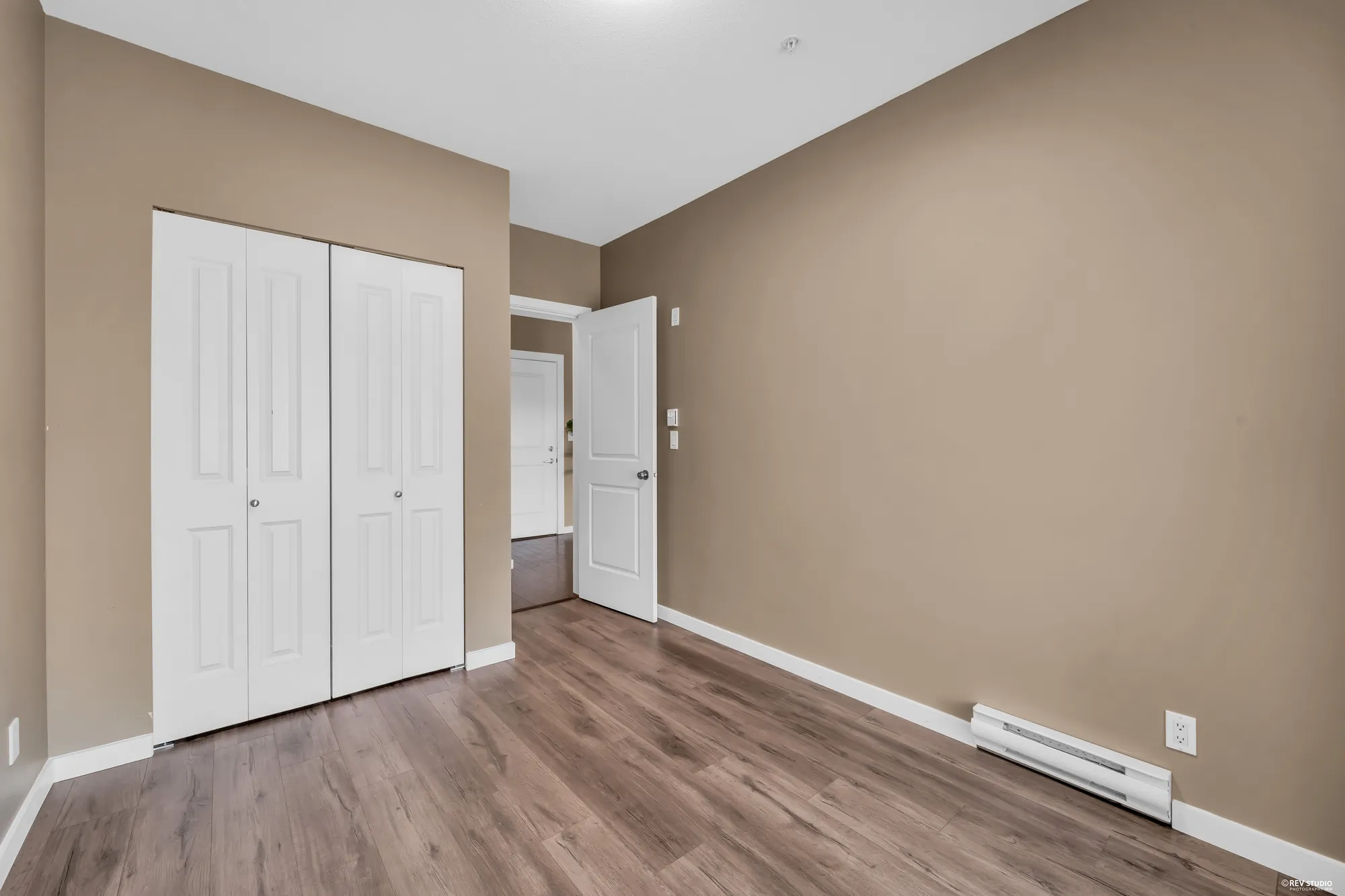 A bedroom wall with built-in closet doors and the door to the hall