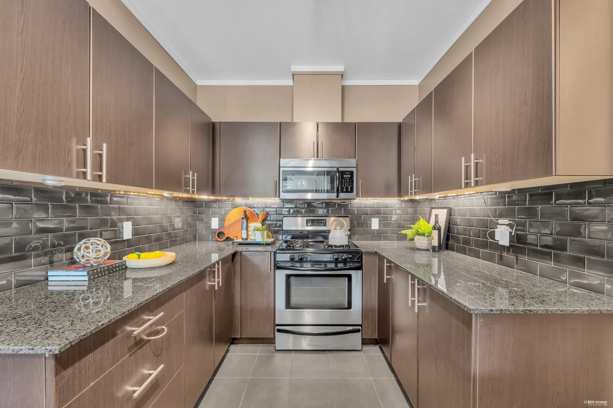The kitchen with granite counters, glass tile backsplash and a stainless gas range