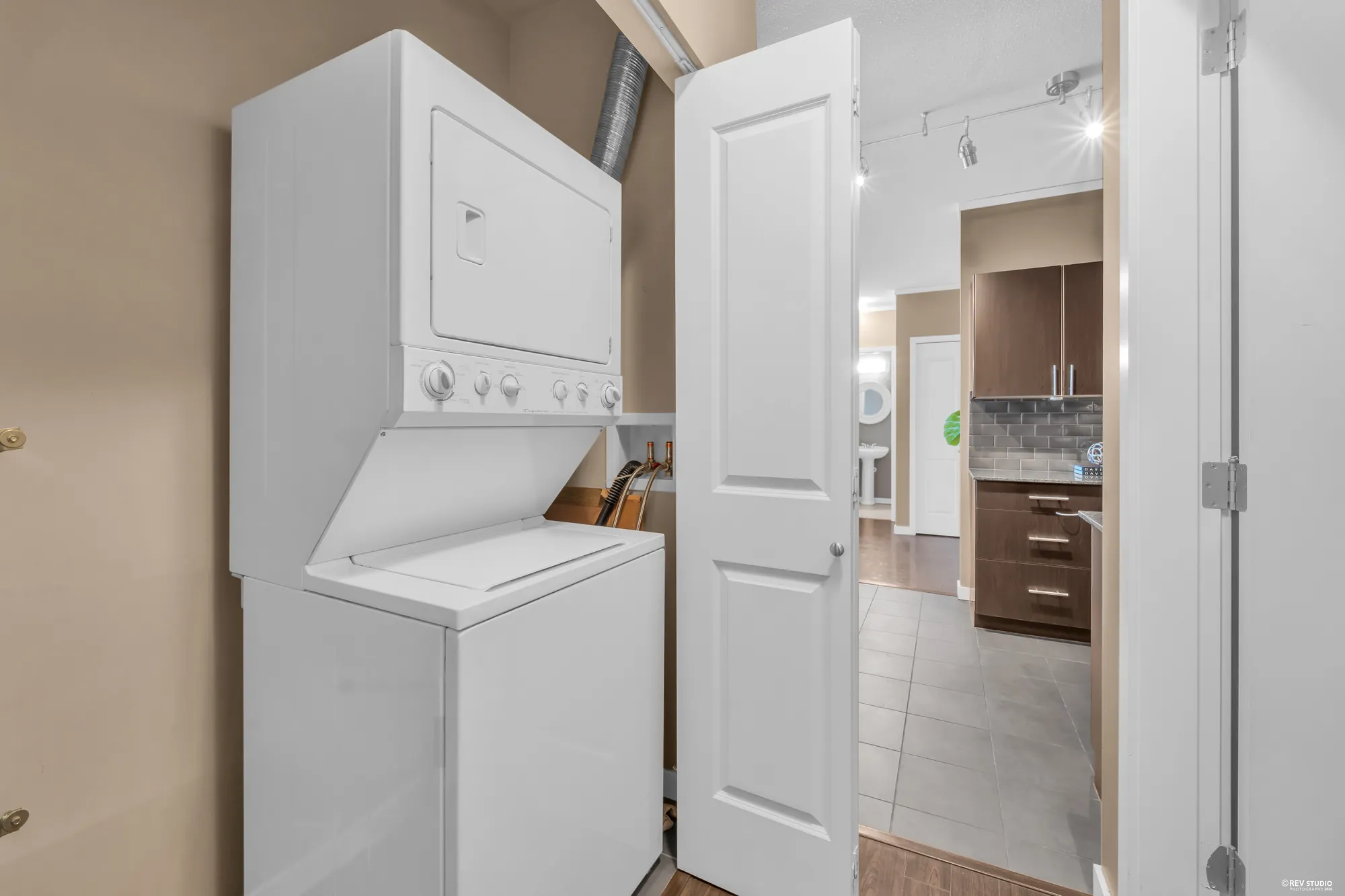 A stacked washer and dryer in a cupboard off the hall